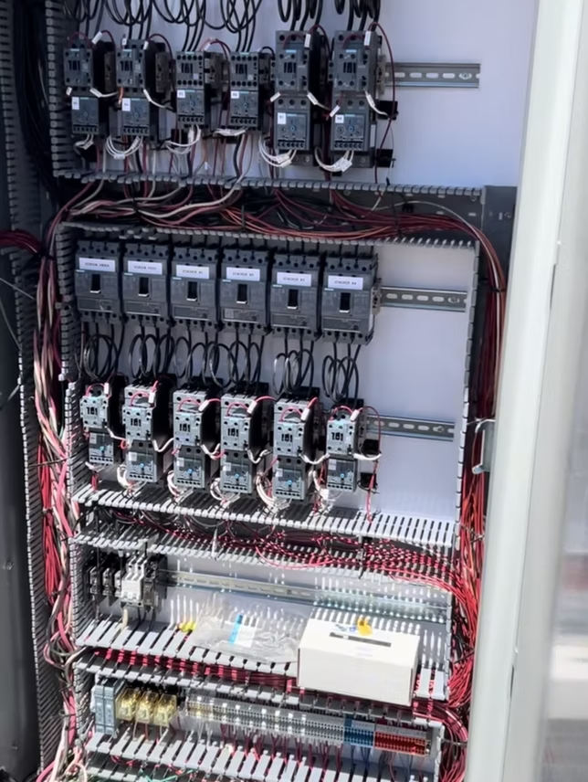 Electrical control panel with multiple relays, wiring, and terminal blocks.