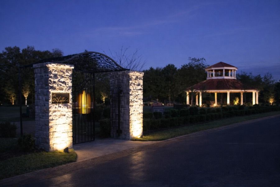 Summertown, TN Cemeteries entrance at dusk with lit stone gate pillars and pavilion gazebo beyond.