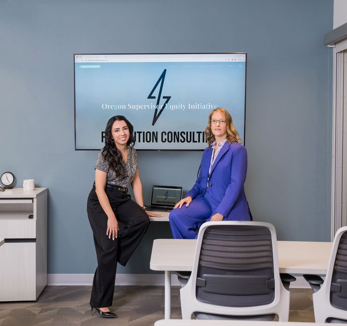 Two women are posing for a picture in front of a sign that says Revolution consulting