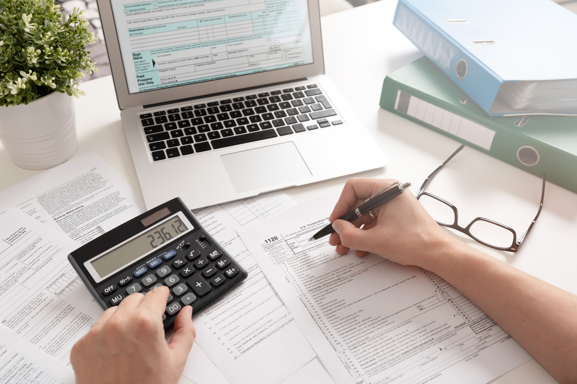 A person is using a calculator and writing on a piece of paper.