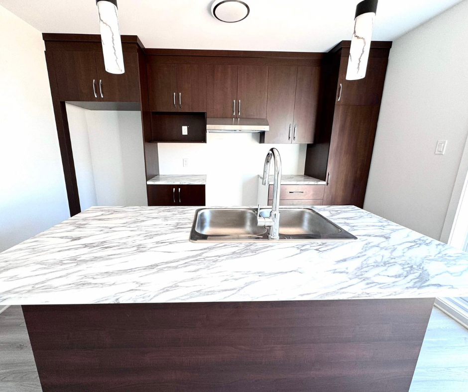 Cuisine moderne avec armoires en bois foncé, îlot de comptoir en marbre blanc et évier en acier inoxydable.