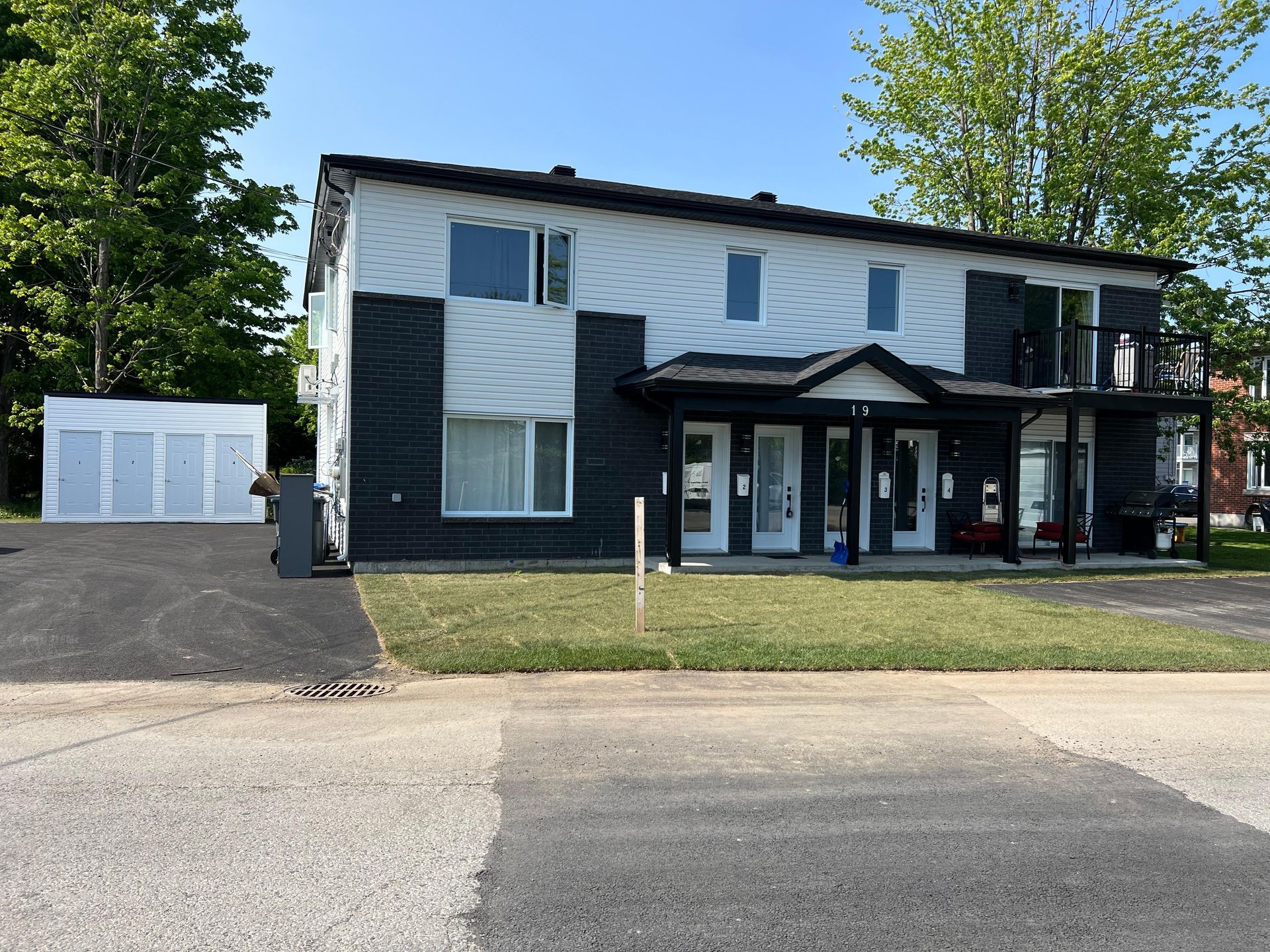Immeuble de deux étages aux murs noirs et blancs. Il dispose d'une véranda et d'un balcon, ainsi que d'un petit garage sur la gauche.
