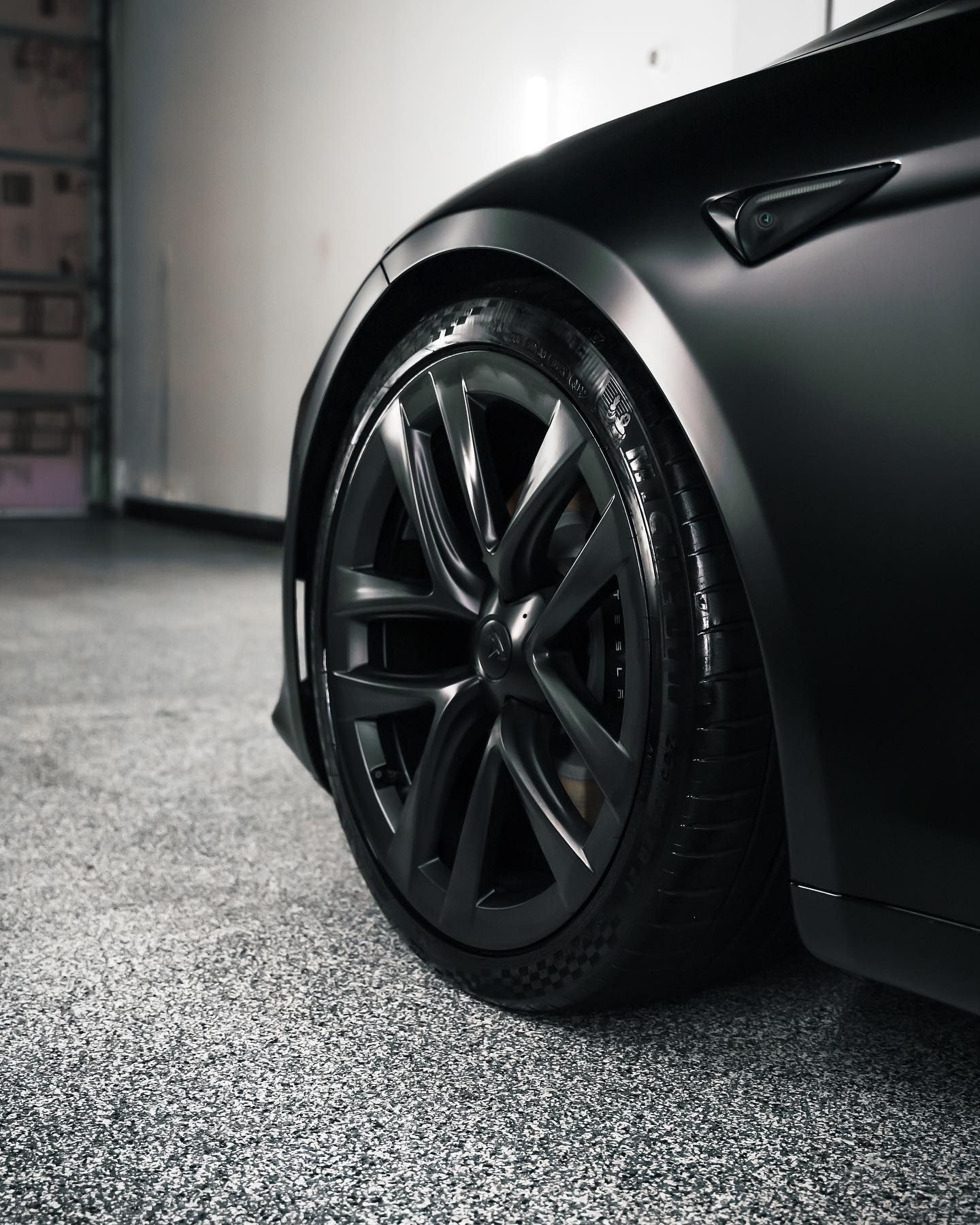 A black tesla model 3 is parked in a garage