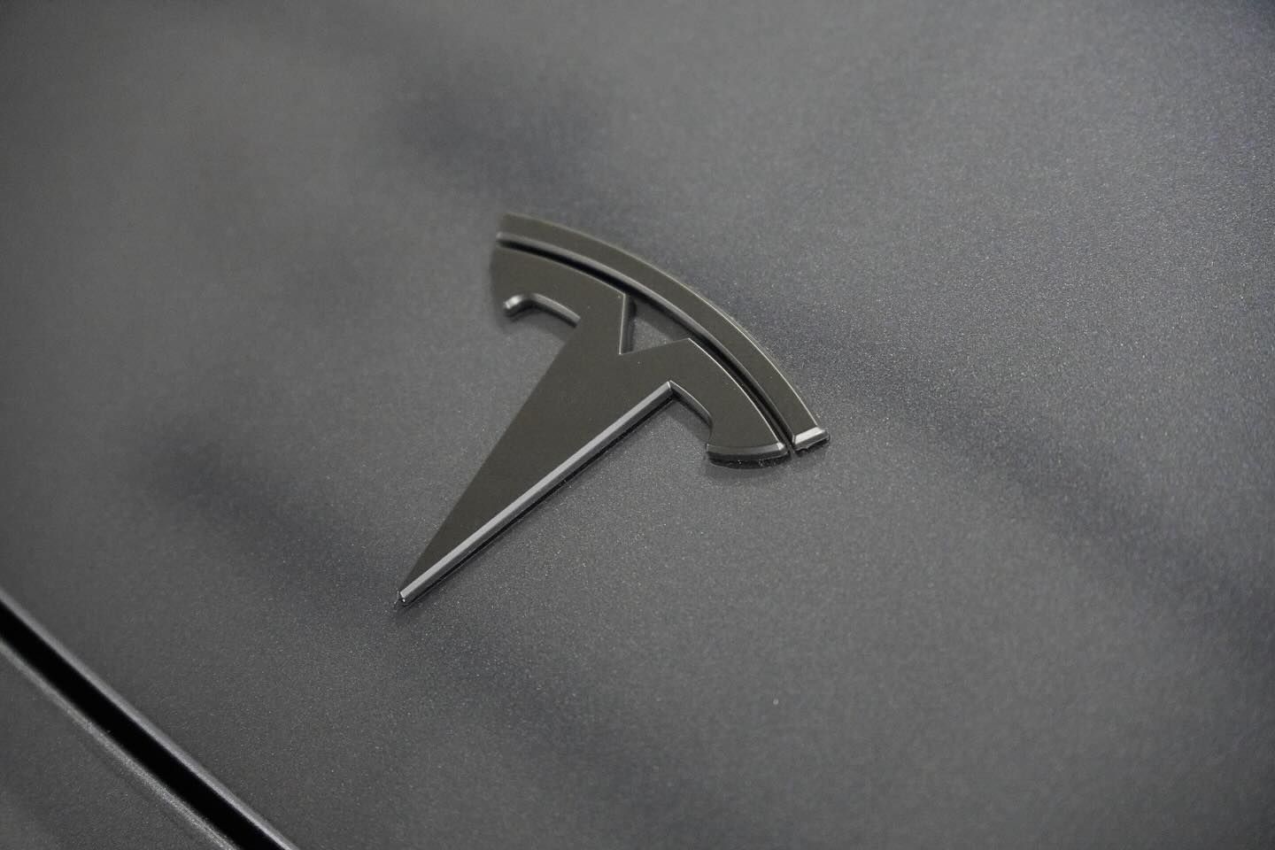 A close up of a tesla logo on the side of a car.
