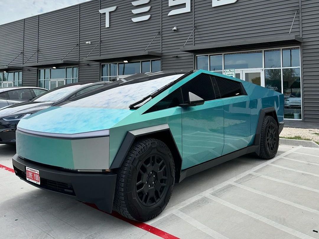 A tesla cybertruck is parked in front of a tesla store.