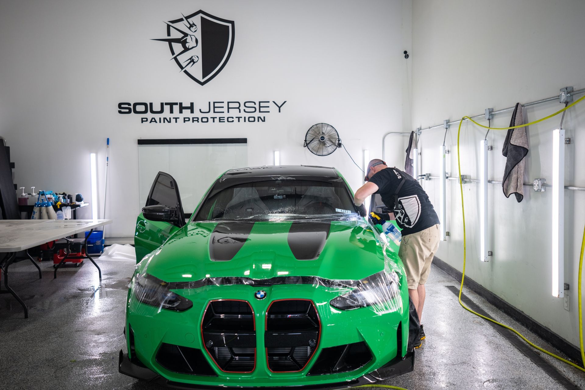 A man is working on a green car in a garage.
