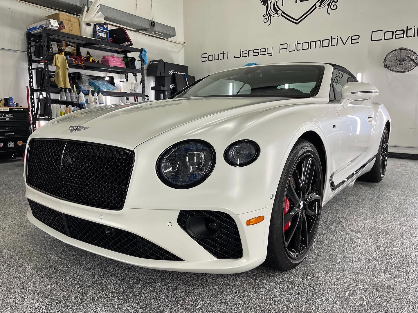 A white bentley continental gt is parked in a garage.