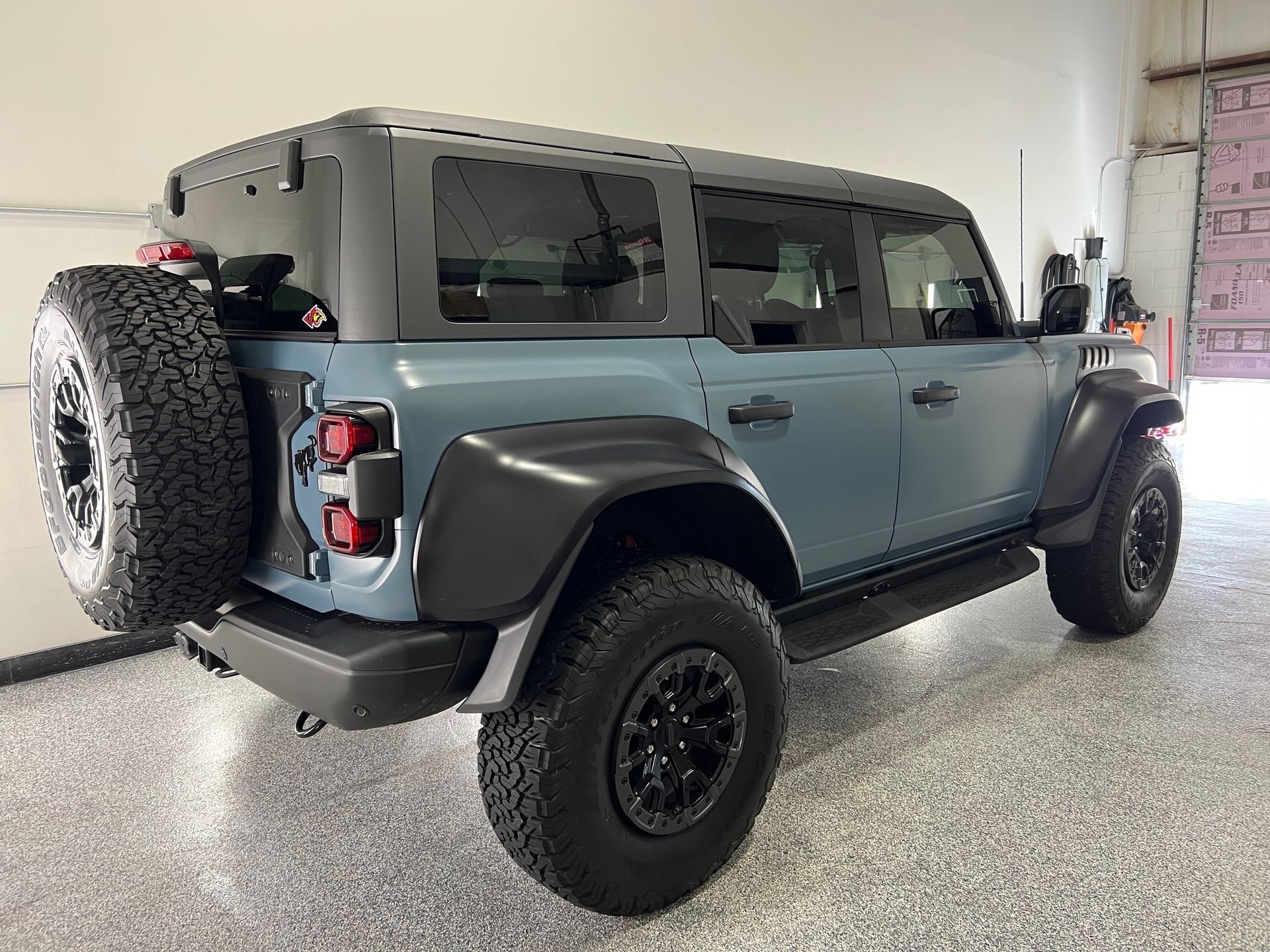 A blue jeep is parked in a garage next to a garage door.
