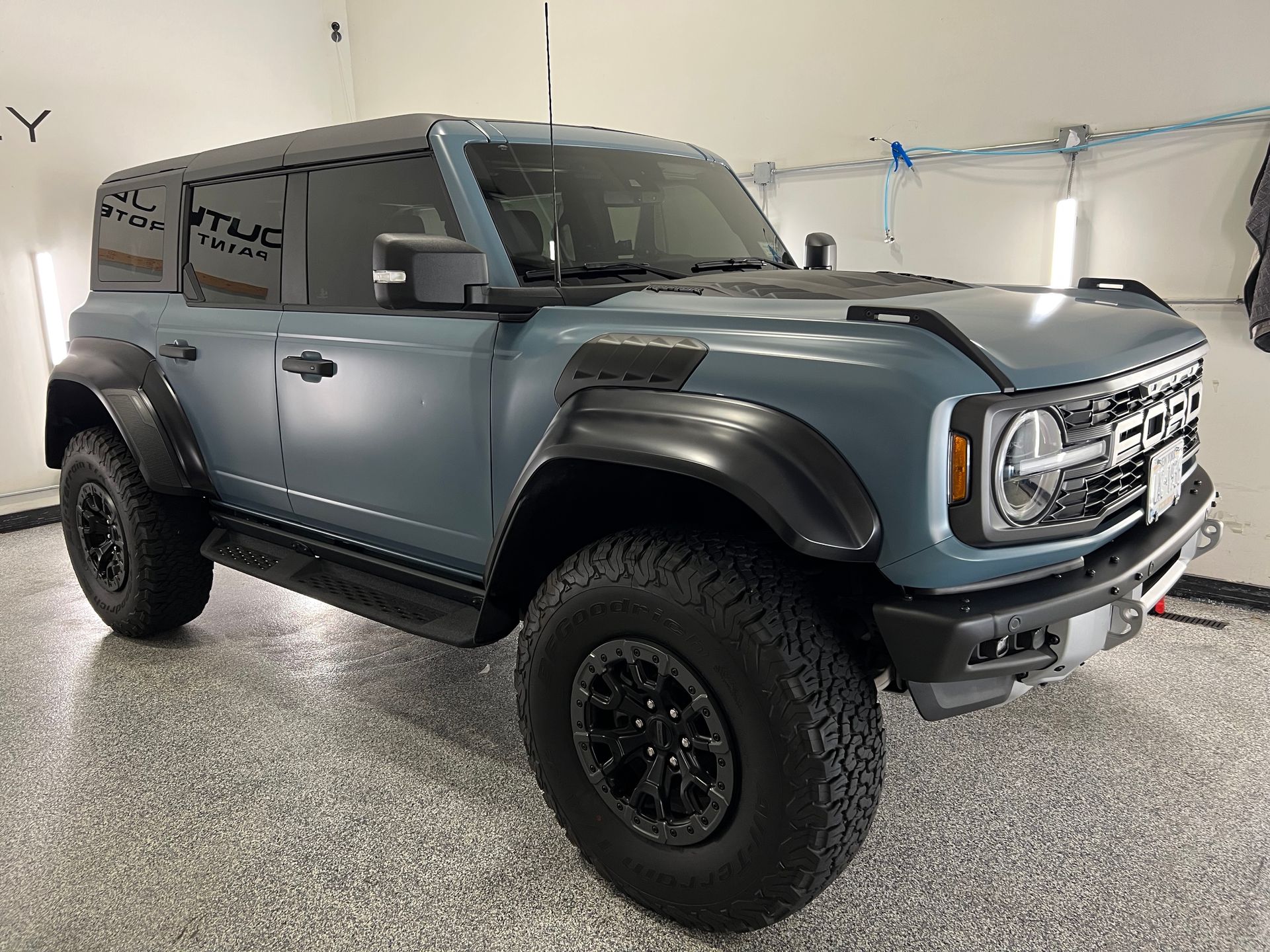 A blue ford bronco is parked in a garage.