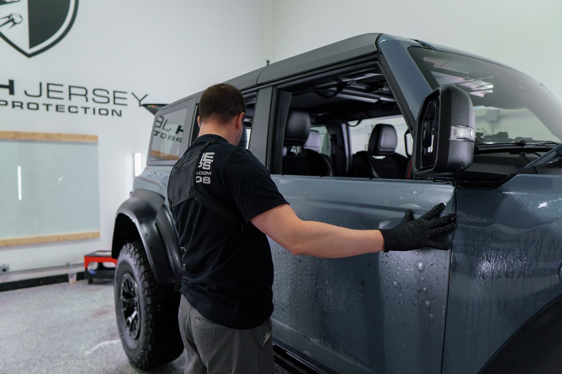 A man is working on a ford bronco in a garage.