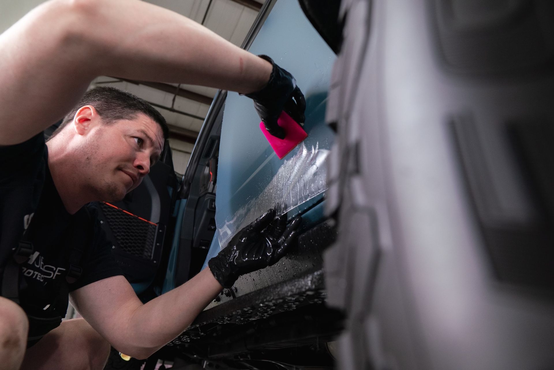 A man is wrapping a car with plastic wrap.