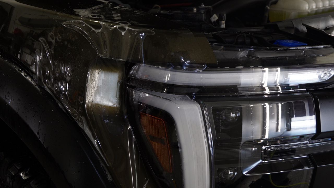 A close up of a car headlight covered in plastic wrap.