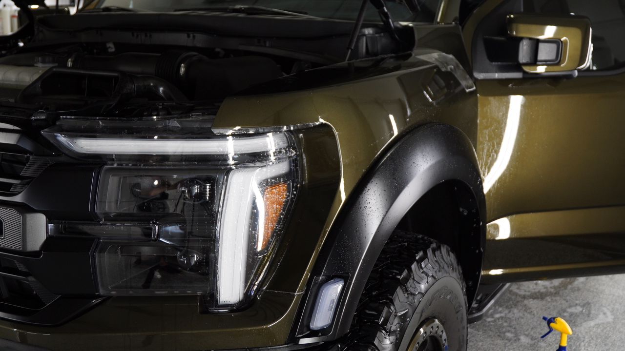A close up of a truck with the hood up in a garage.
