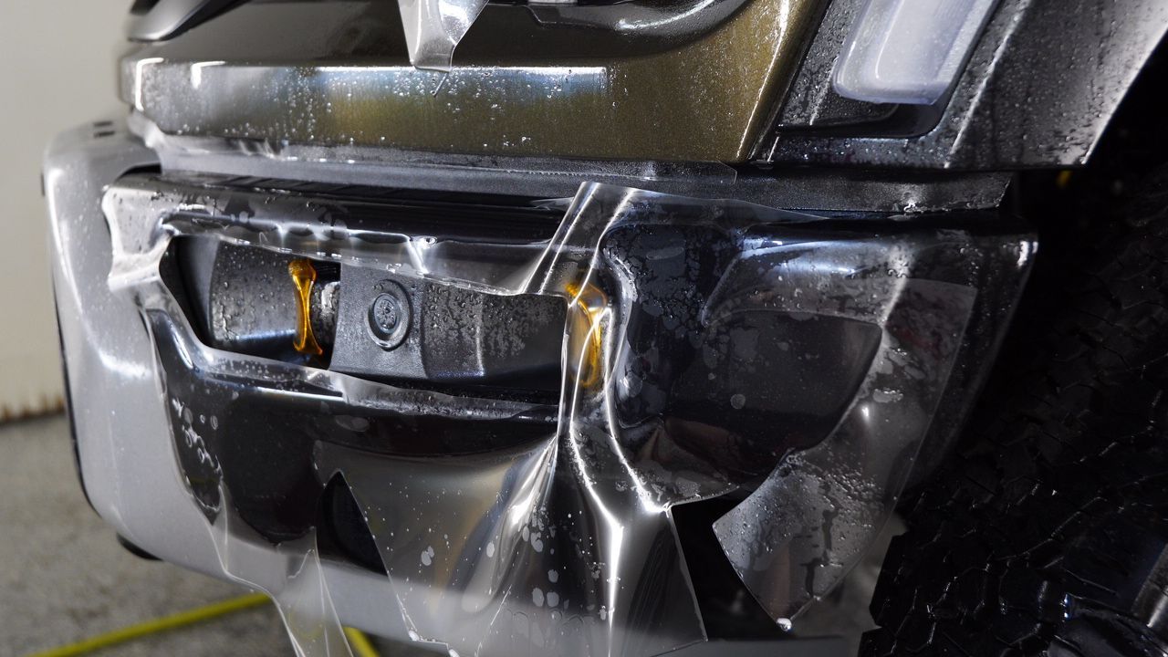 A close up of a car 's bumper with a hose attached to it.