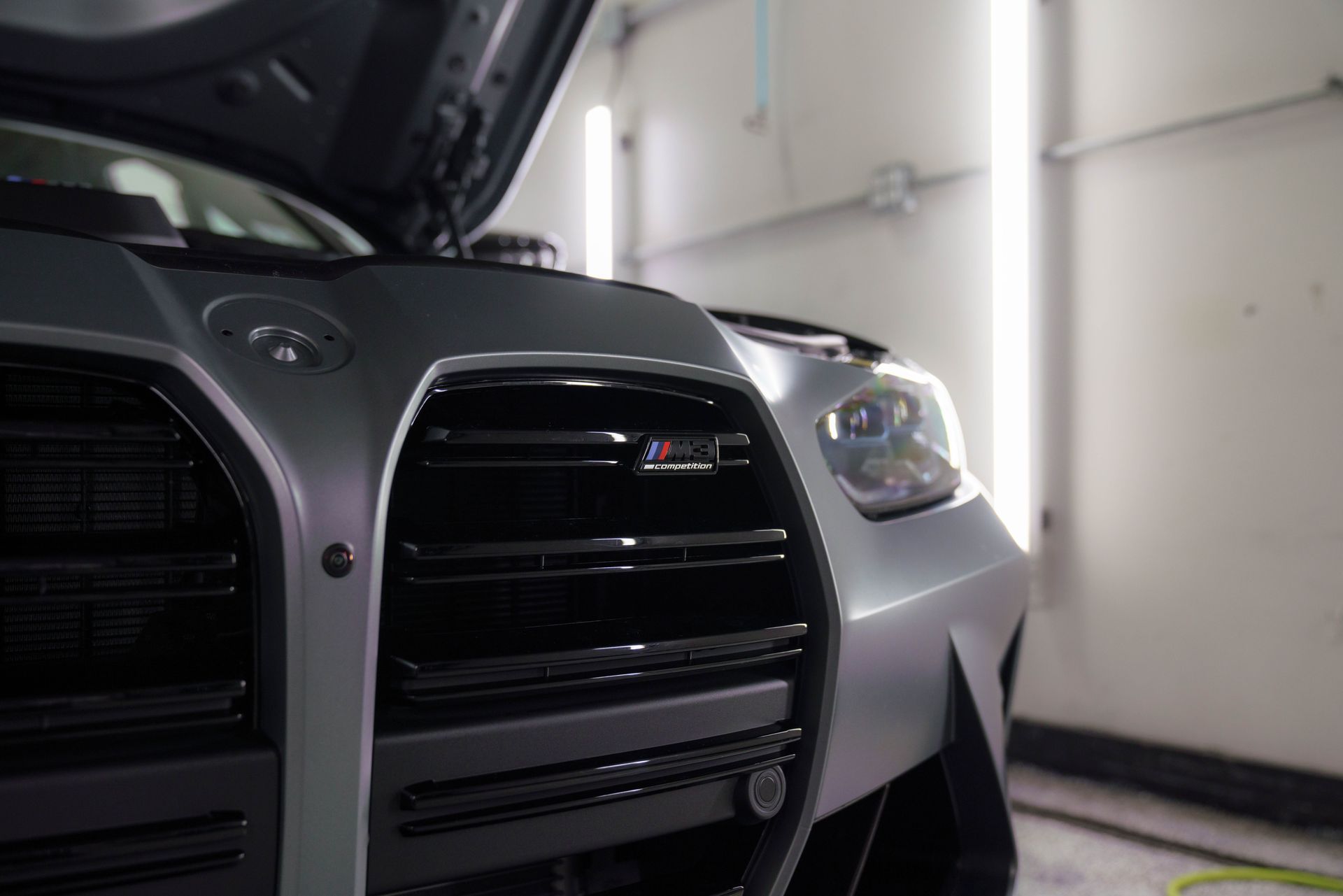A close up of a car with the hood up in a garage.