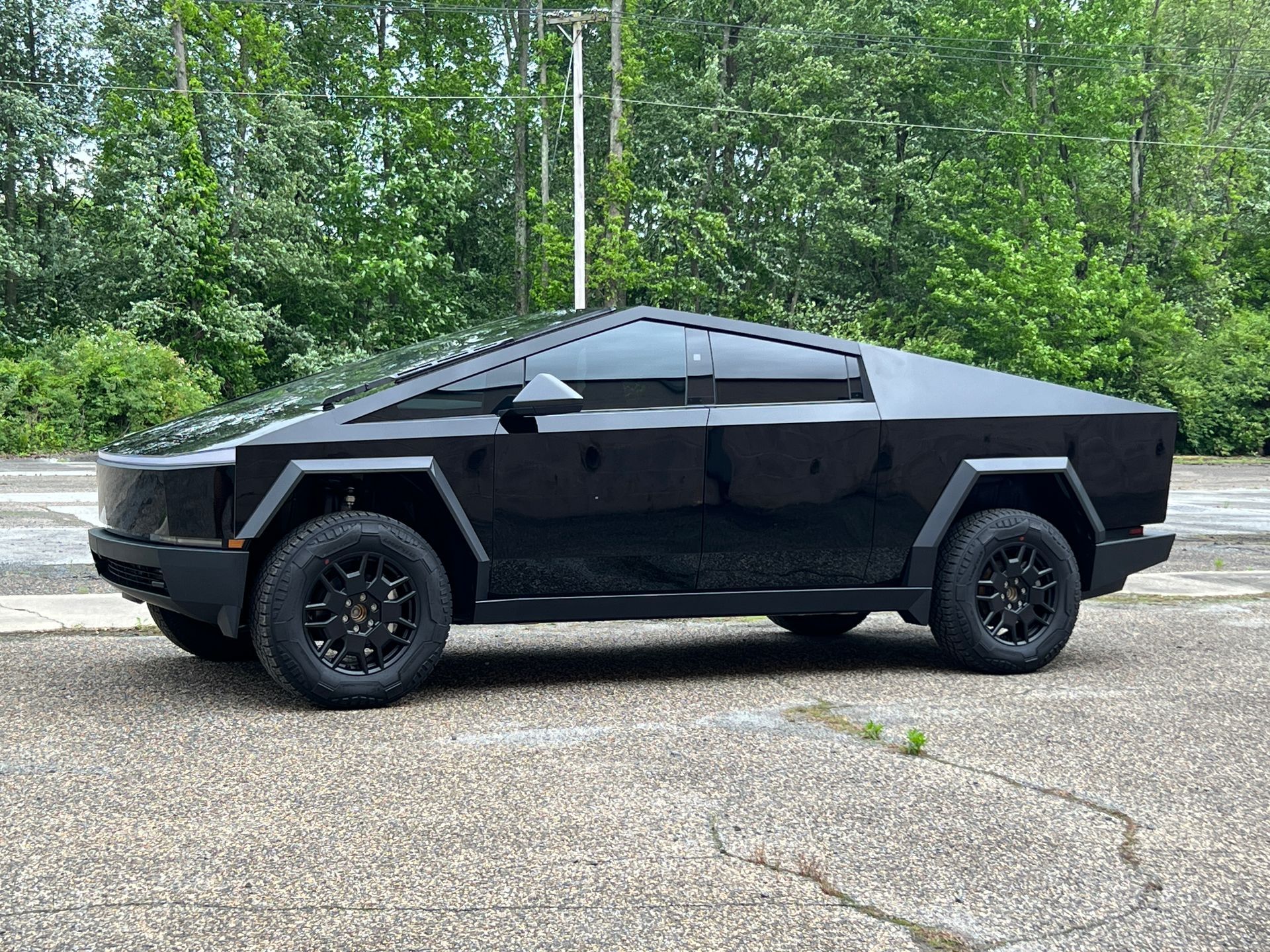 A black tesla cybertruck is parked on the side of the road.
