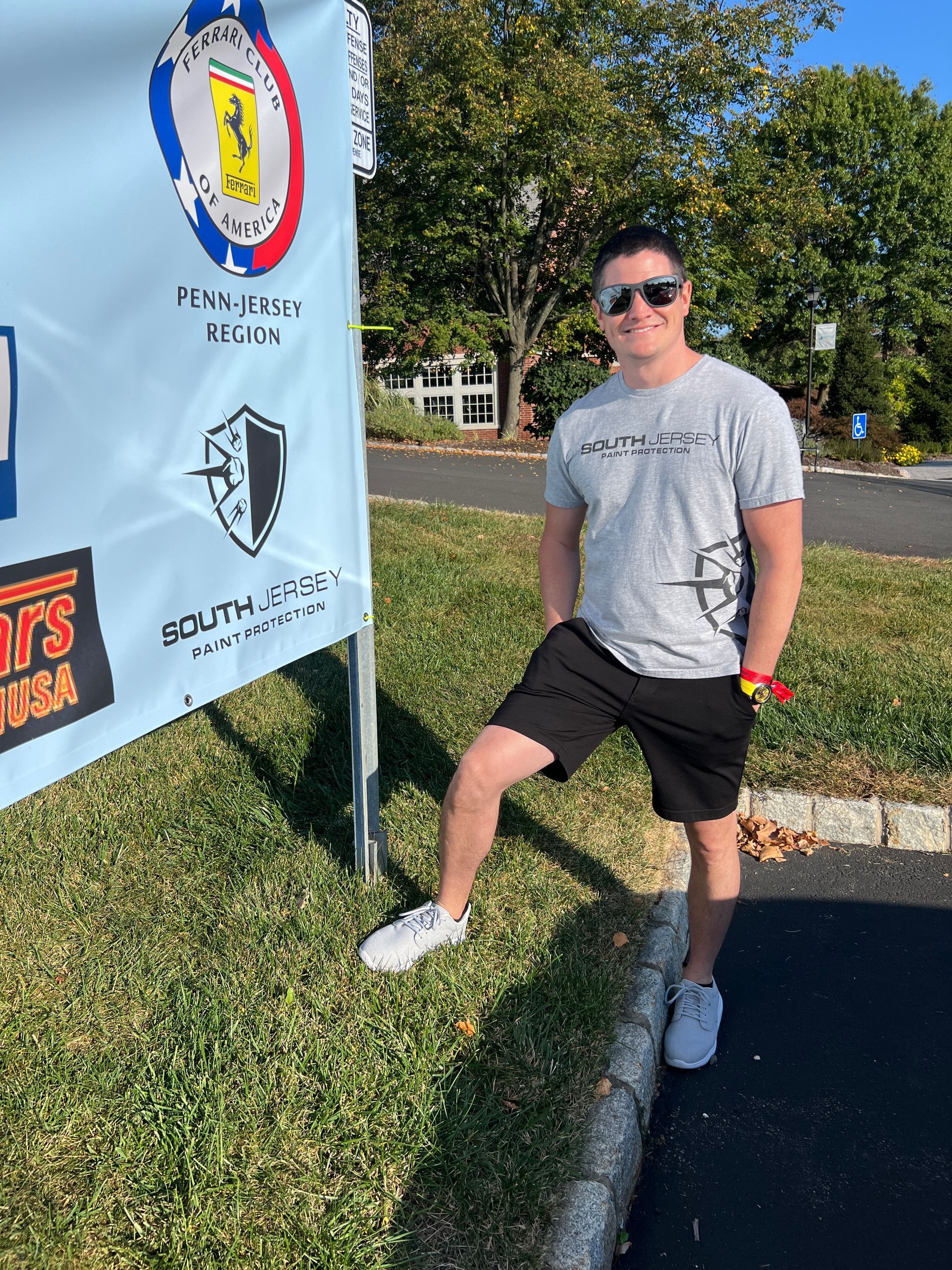 A young man is standing in front of a sign on the side of the road.