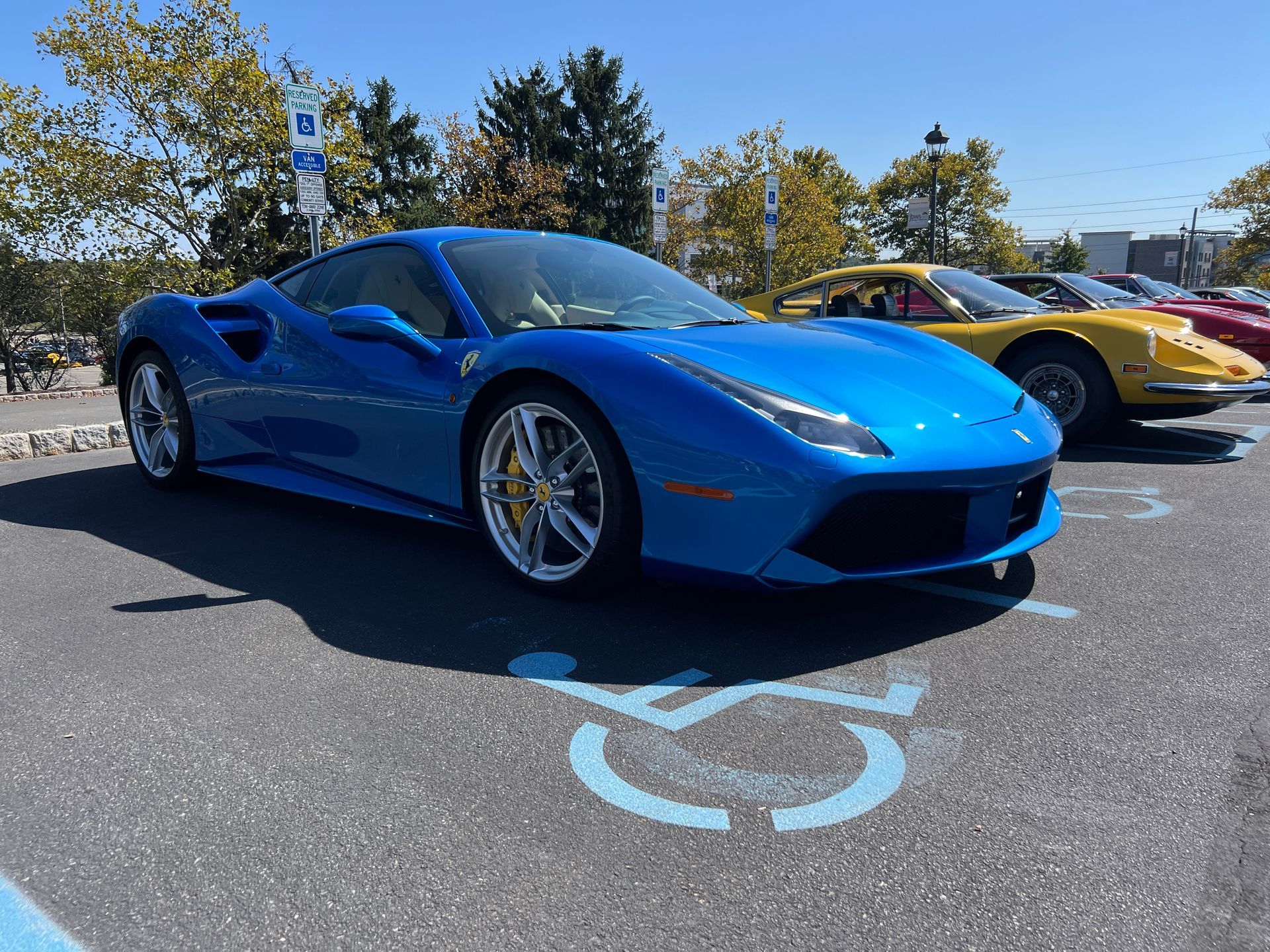 A blue sports car is parked in a handicapped parking spot