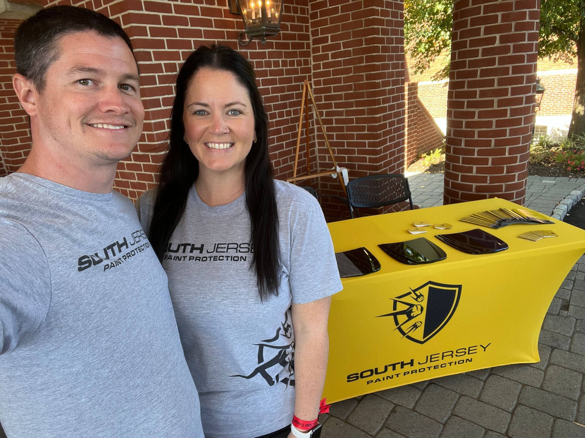 A man and a woman are standing next to each other in front of a yellow table cloth.