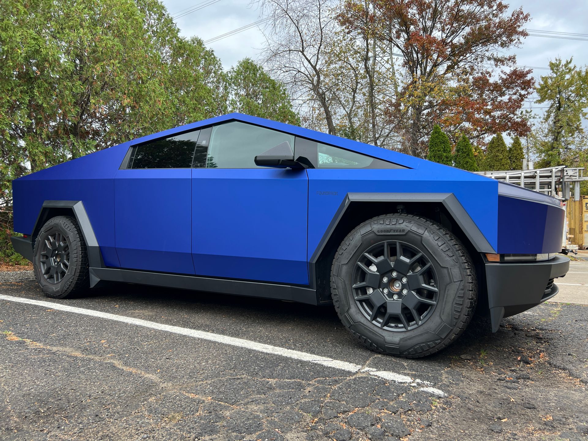 A blue tesla cybertruck is parked in a parking lot.