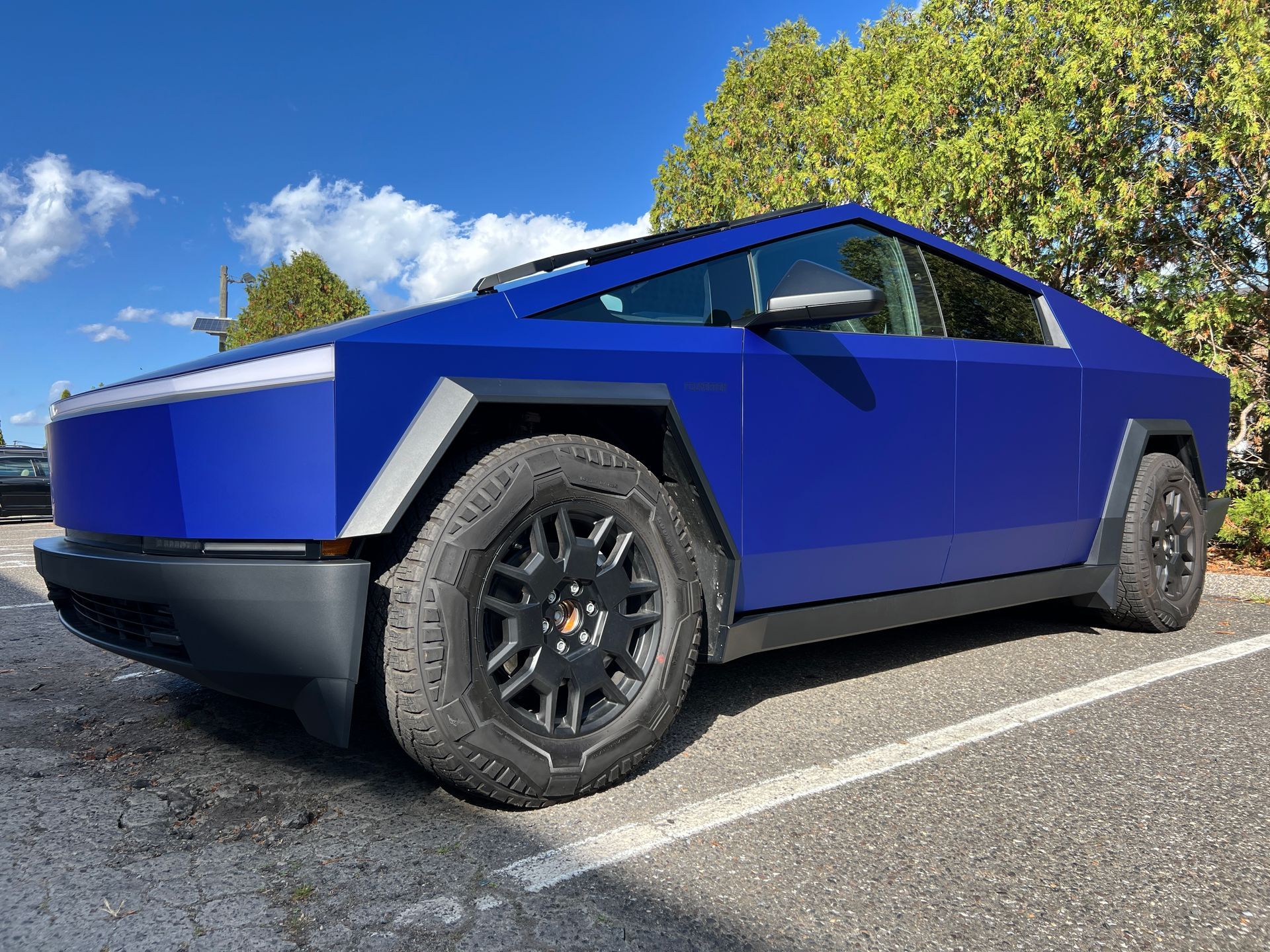 A blue tesla cybertruck is parked in a parking lot.