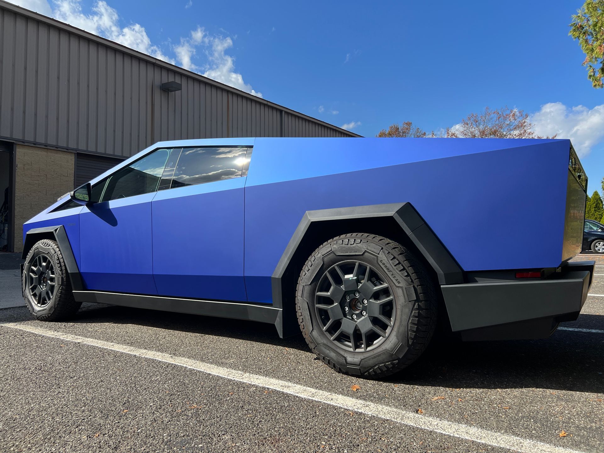 A blue tesla cybertruck is parked in a parking lot.