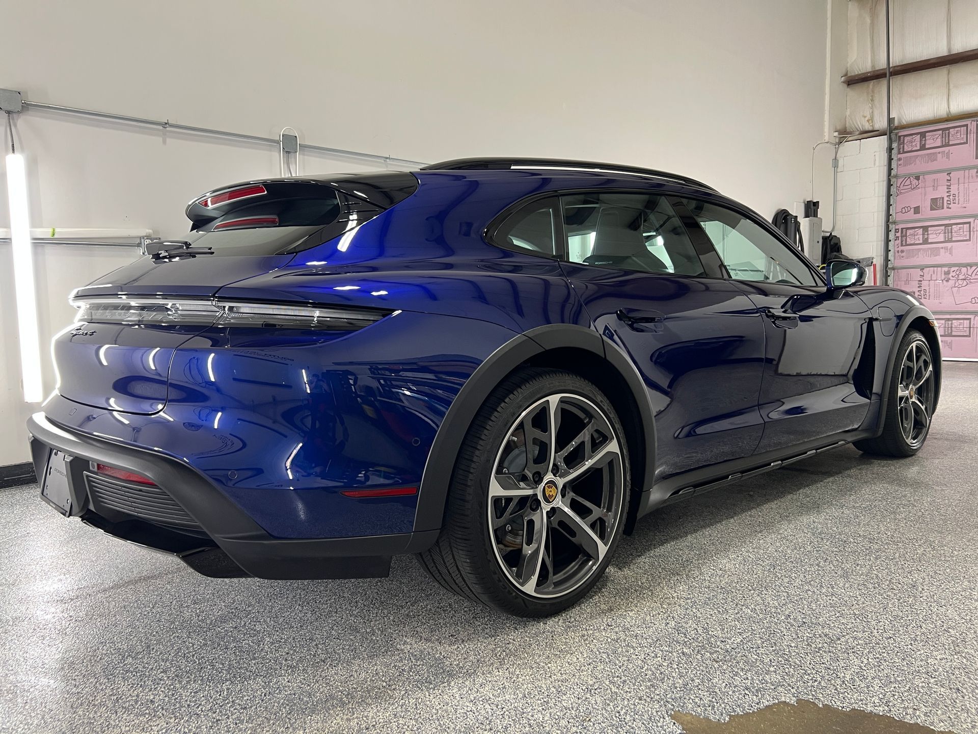 A blue porsche taycan turbo s is parked in a garage.