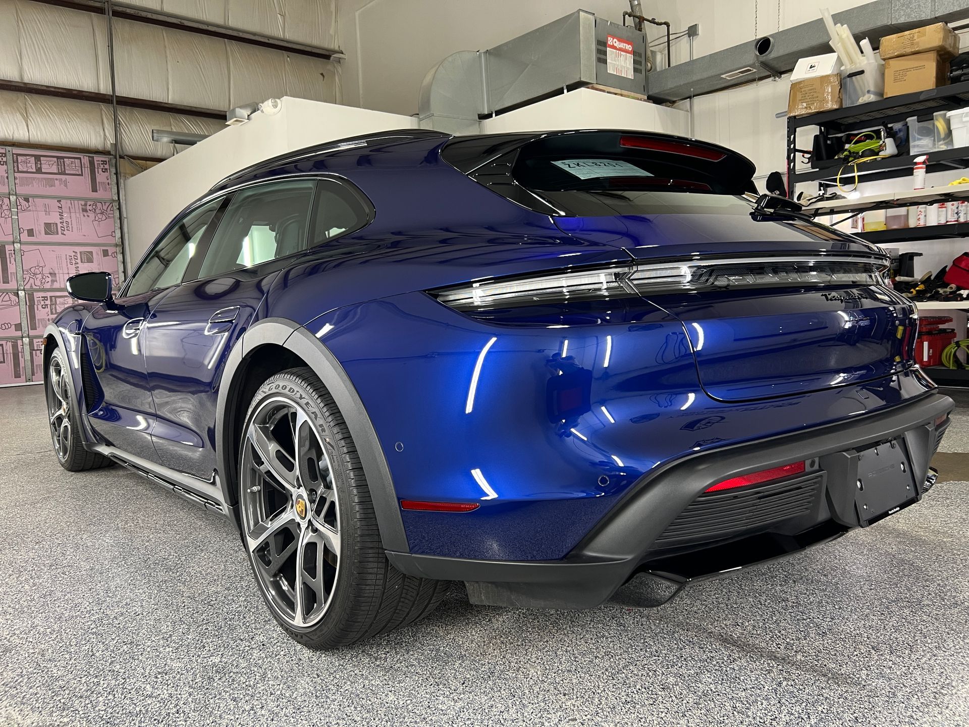 A blue porsche taycan turbo s is parked in a garage.