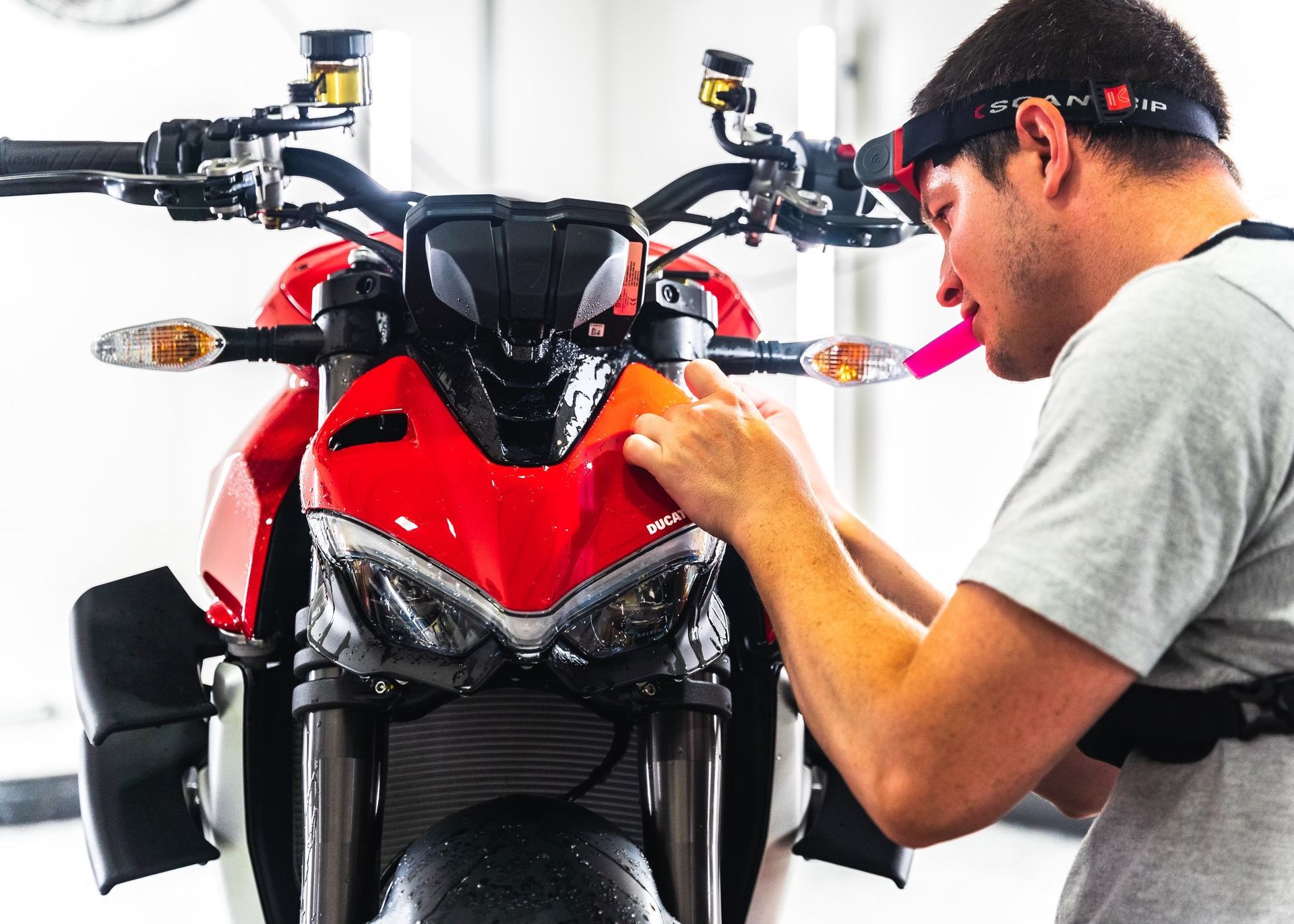 A man wearing a headlight is working on a red motorcycle