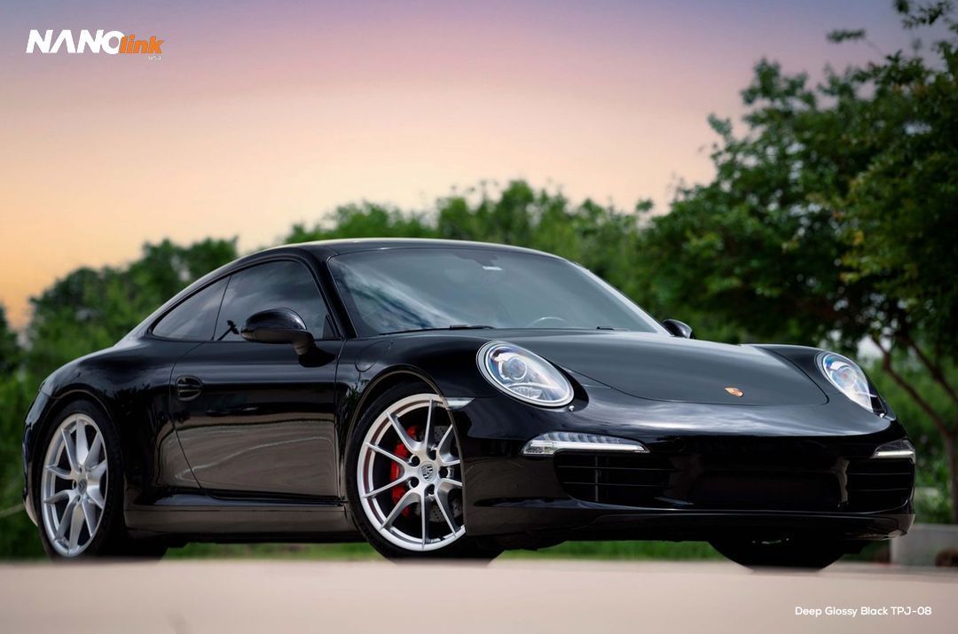 A black porsche 911 is parked on the side of the road.