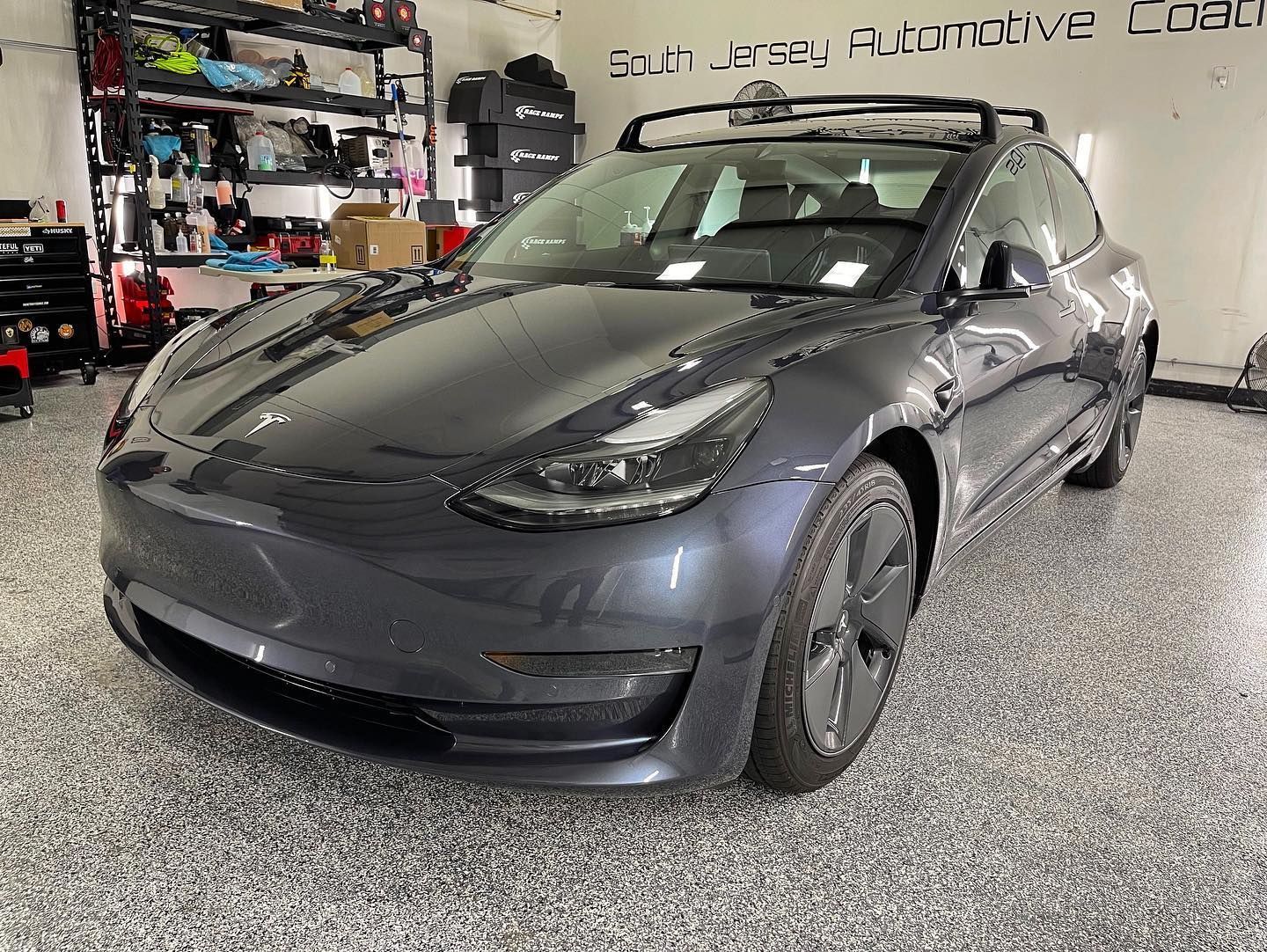 A tesla model 3 is parked in a garage.