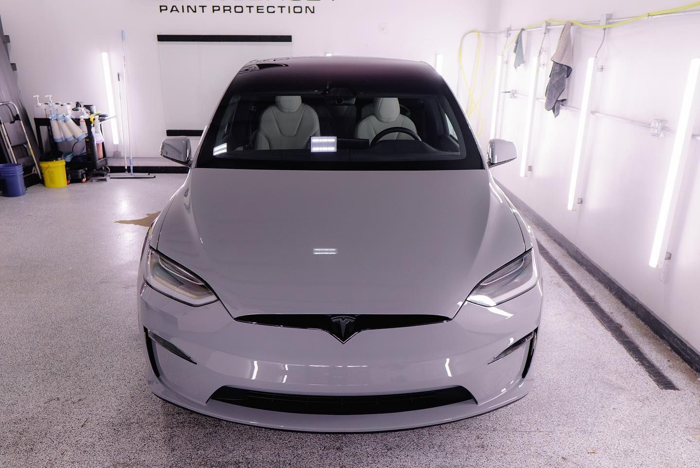 A gray tesla model x is parked in a garage.
