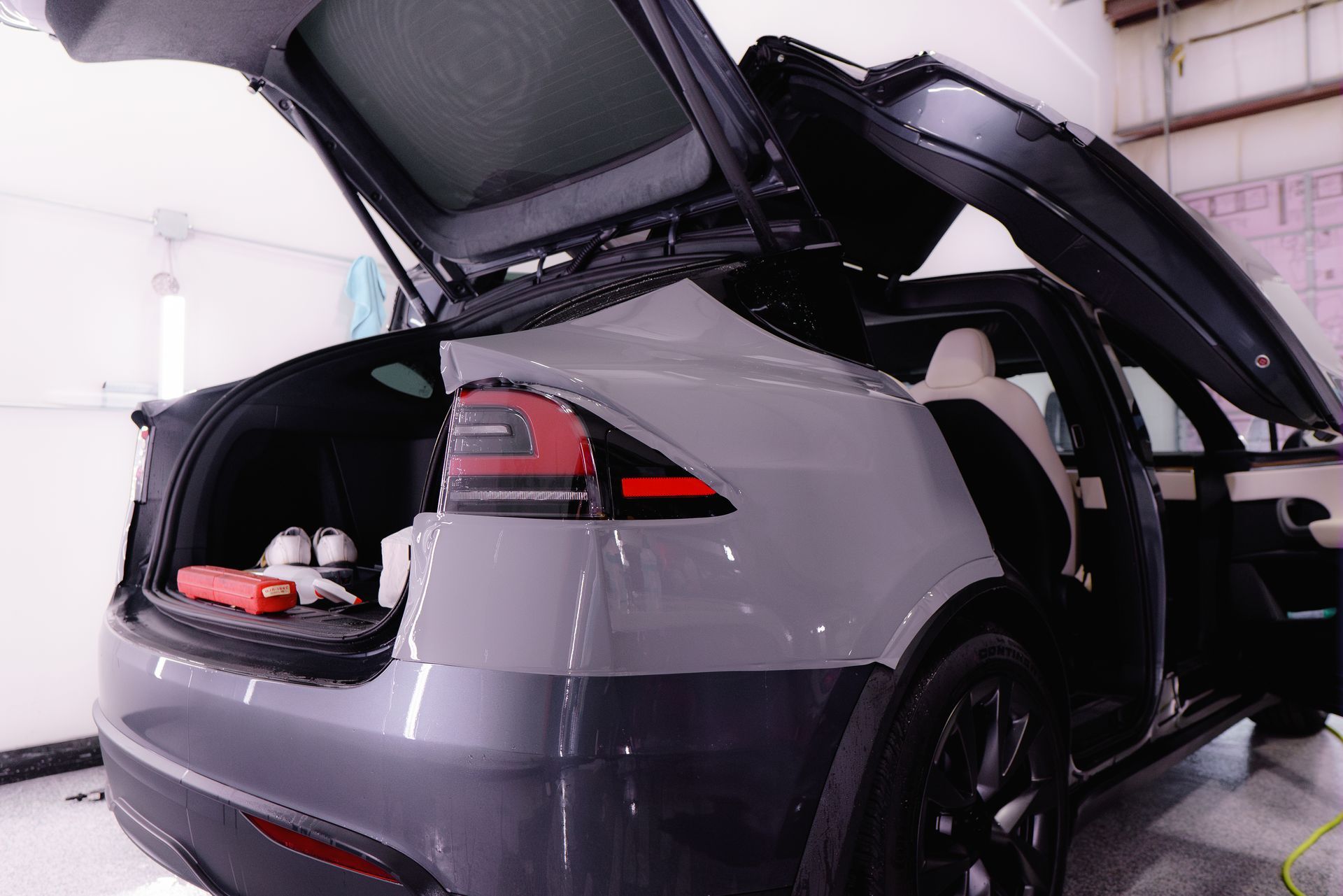 A tesla model x with its trunk open in a garage.