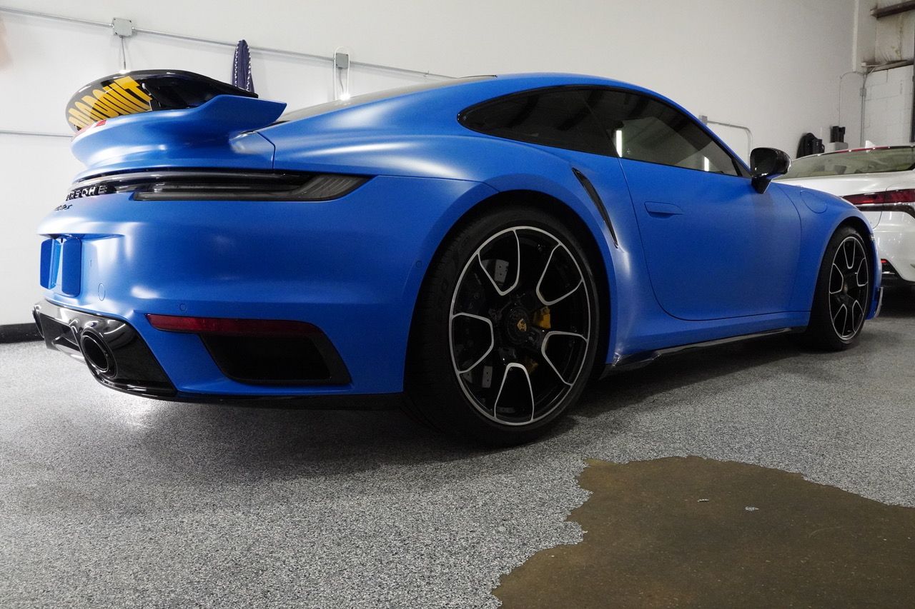 A blue porsche 911 turbo is parked in a garage.
