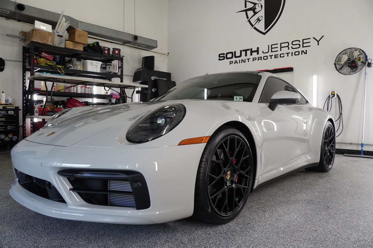 A white porsche 911 is parked in a garage.