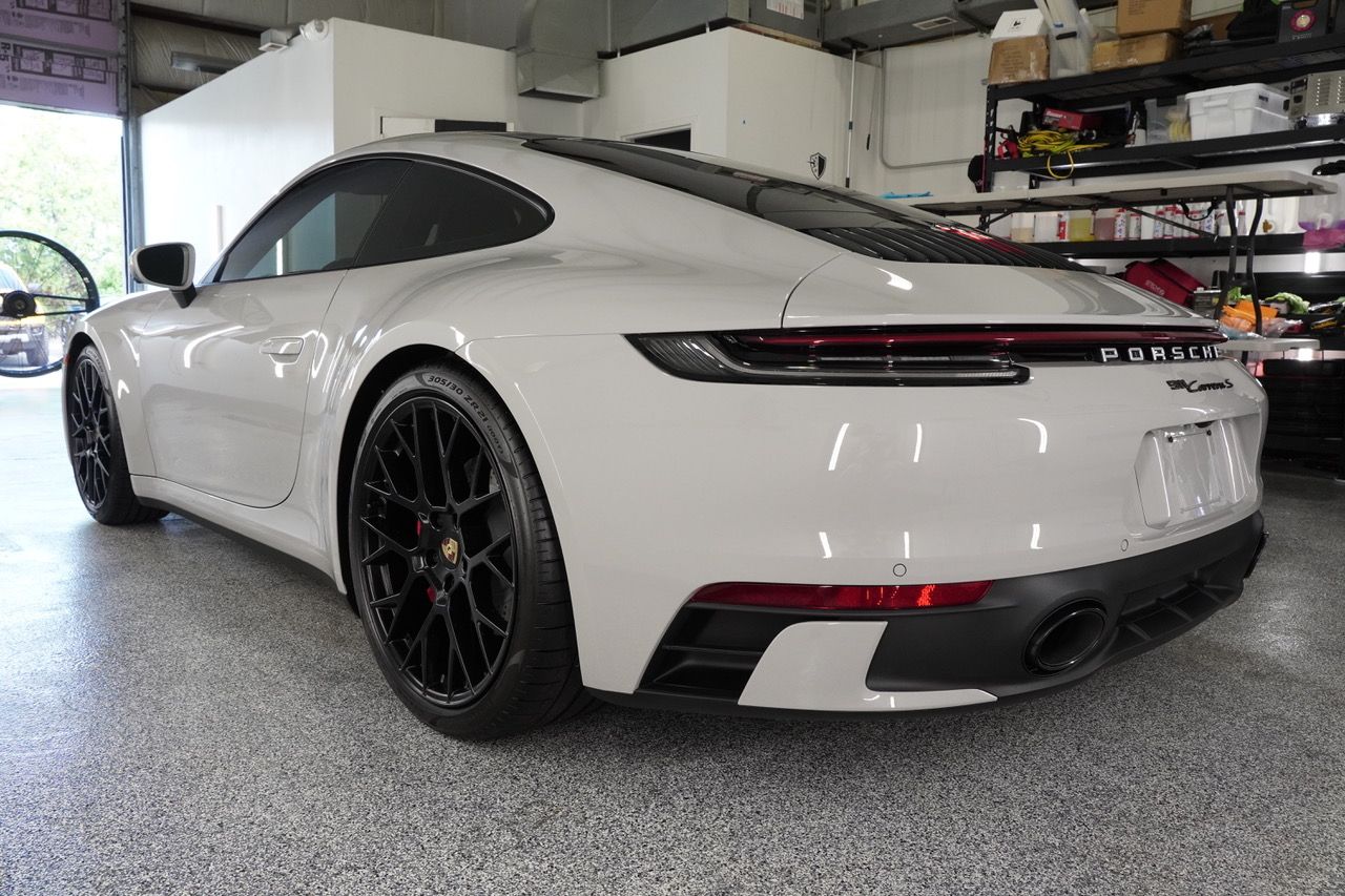 A white porsche 911 is parked in a garage.