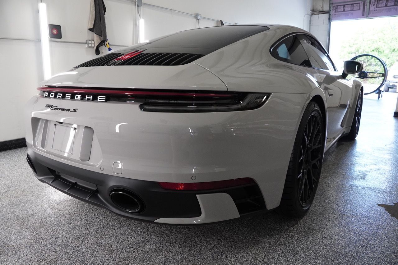 A white porsche 911 is parked in a garage.