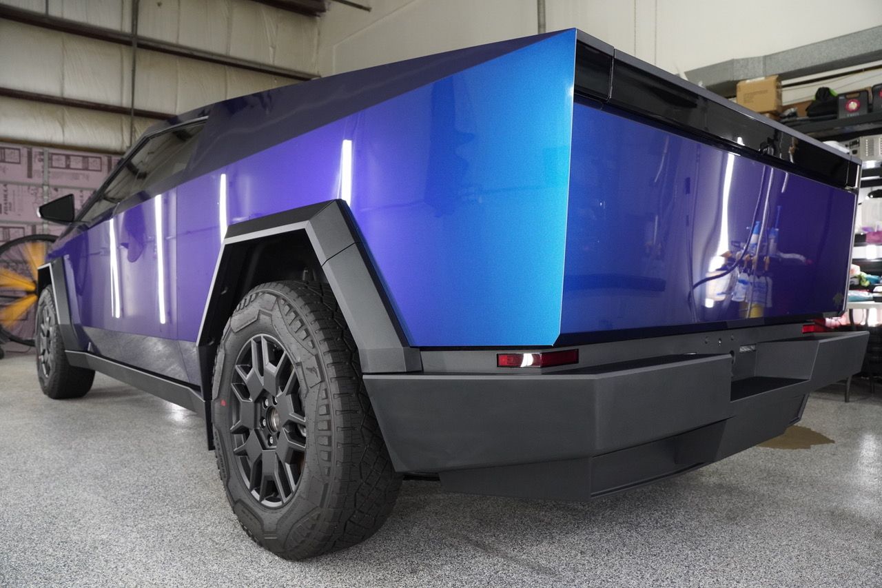 A purple and blue truck is parked in a garage.