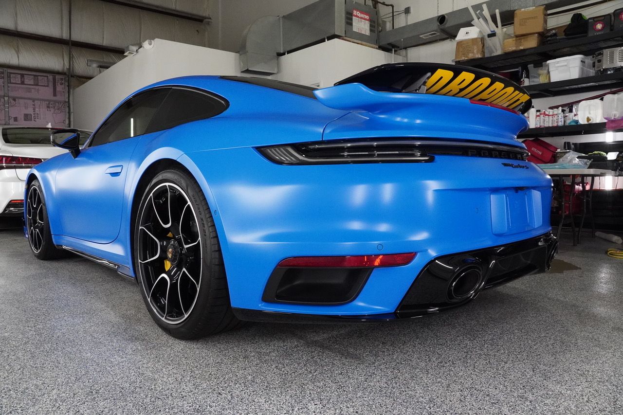 A blue porsche 911 turbo s is parked in a garage.