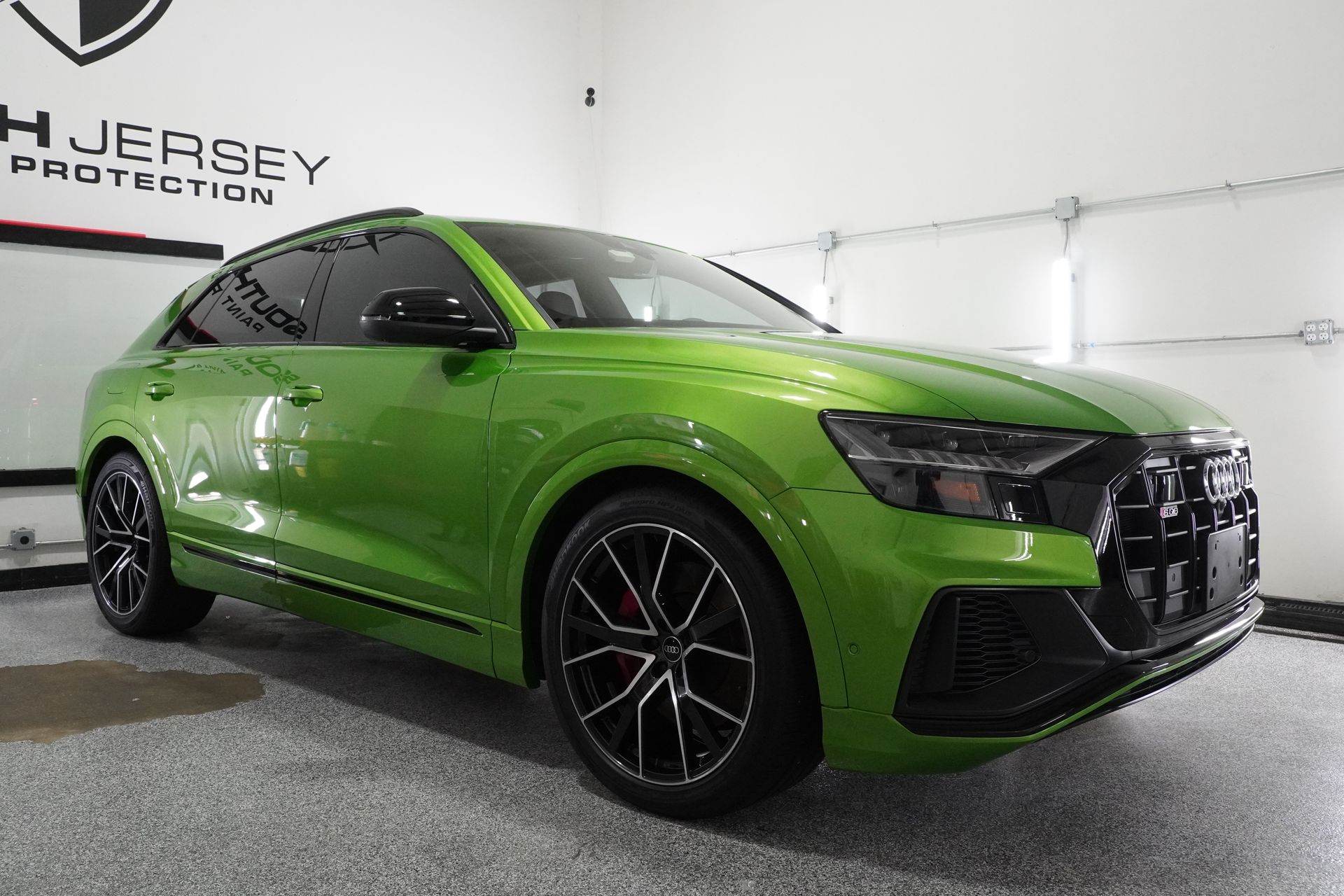 A green audi q8 is parked in a garage.