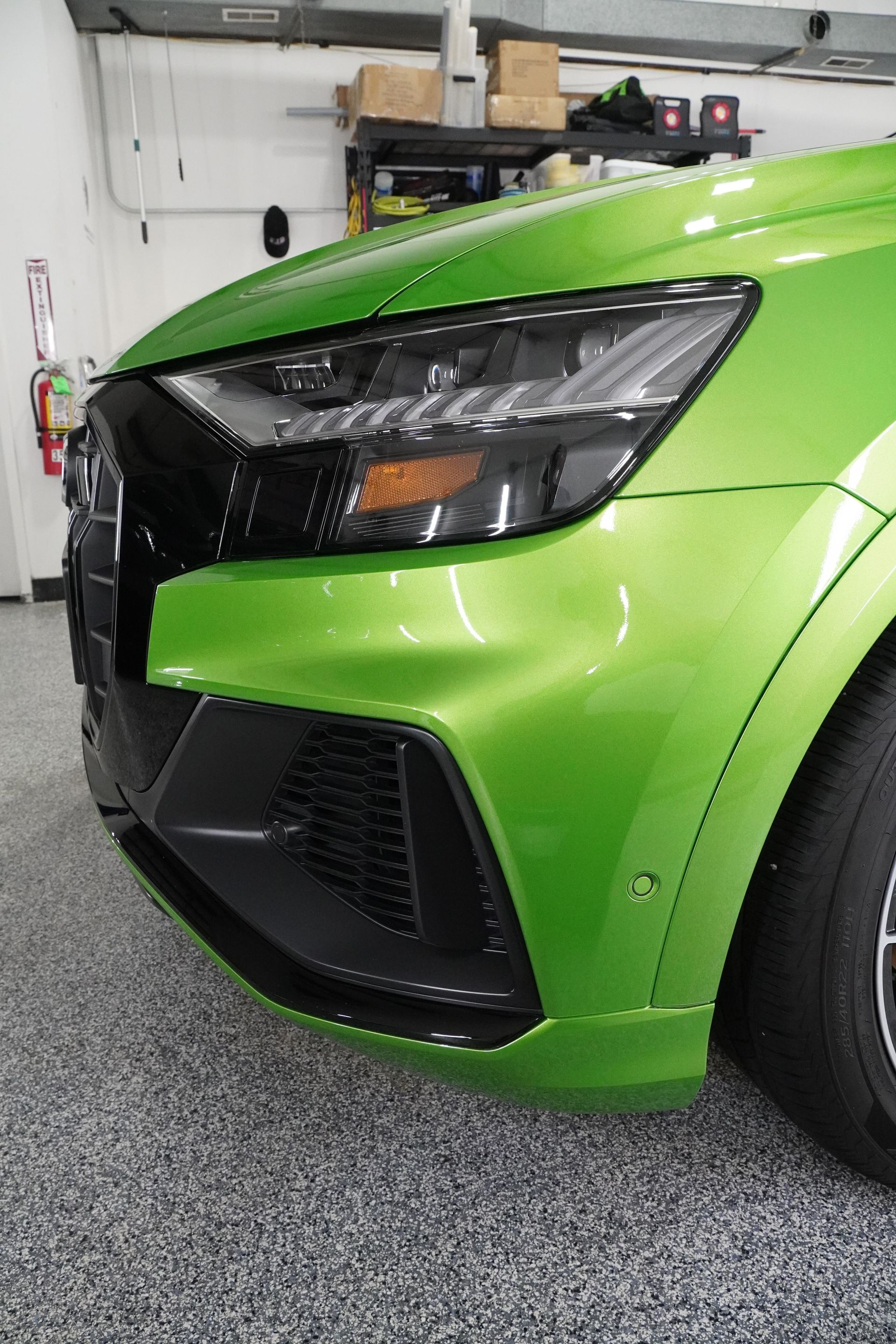 A green car is parked in a garage with a black bumper.