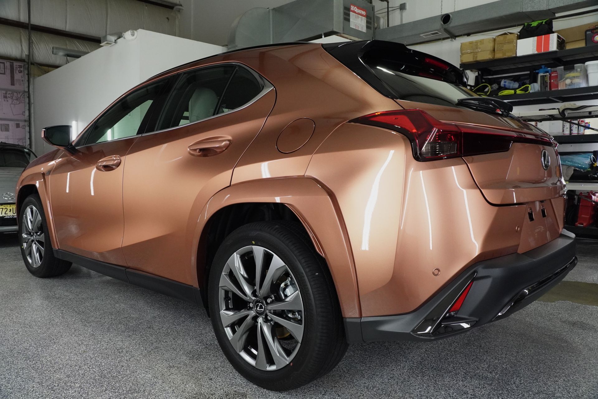 A brown lexus ux is parked in a garage.