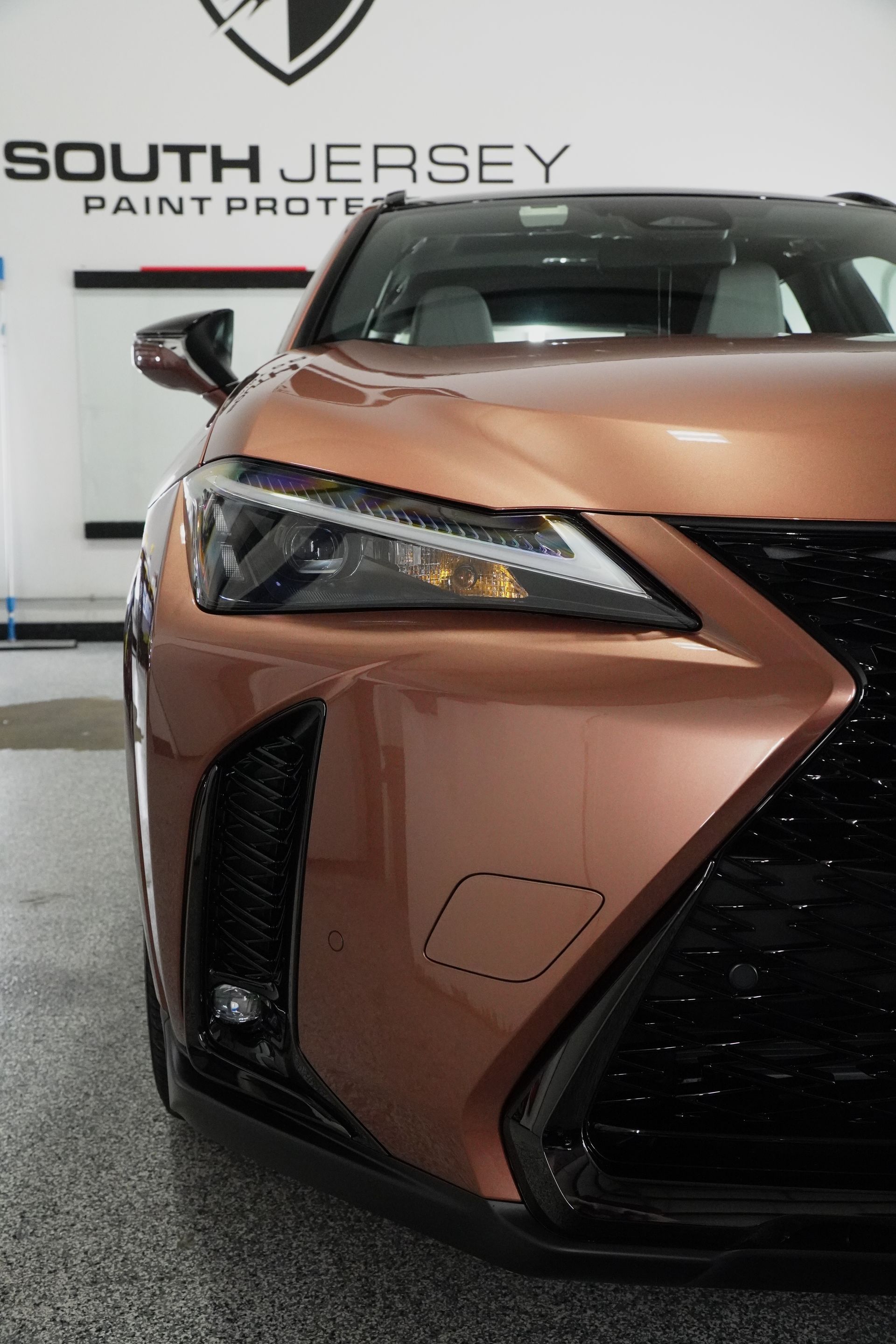 A close up of a car parked in front of a wall that says south jersey paint protection.