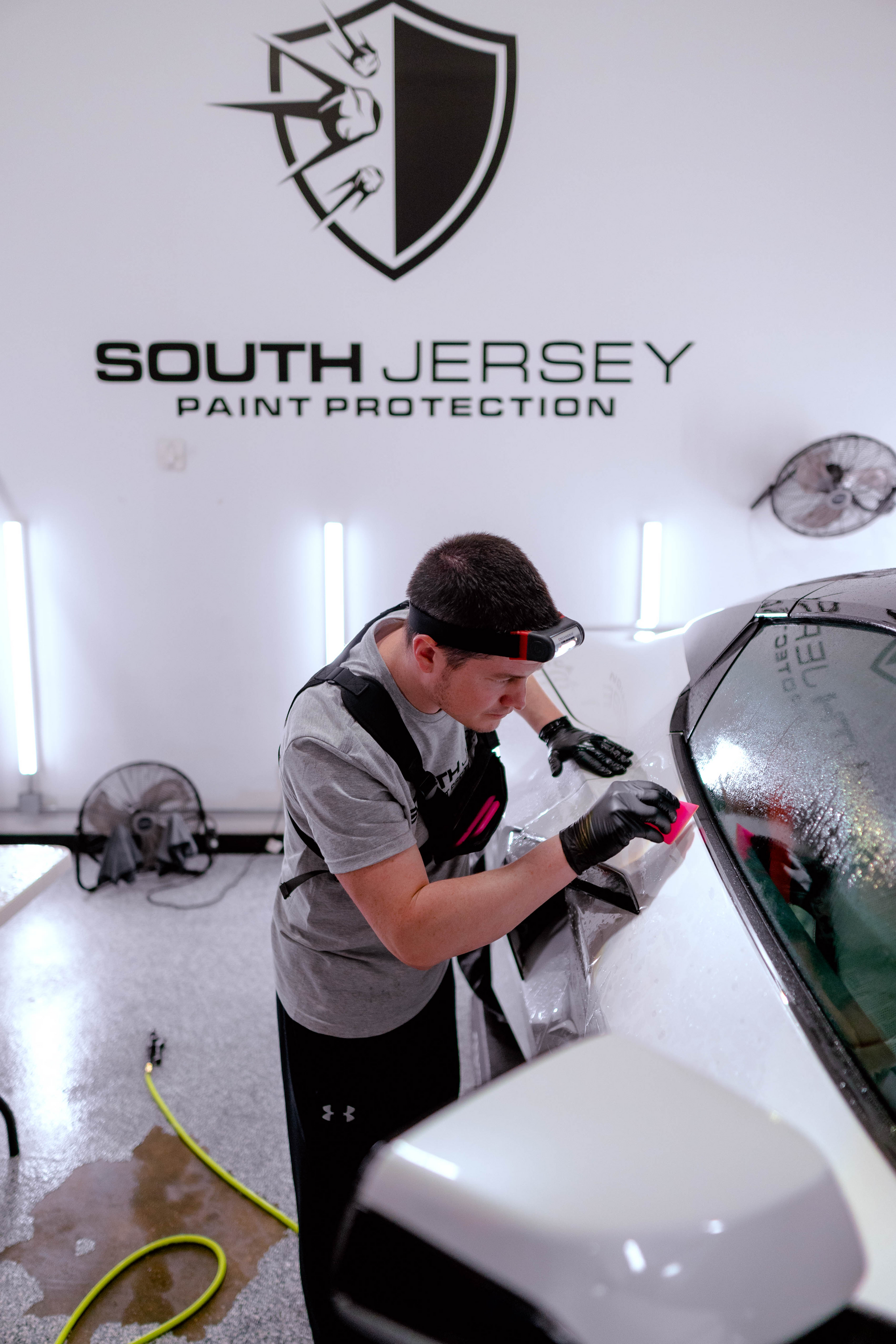 A man is cleaning the windshield of a white car.