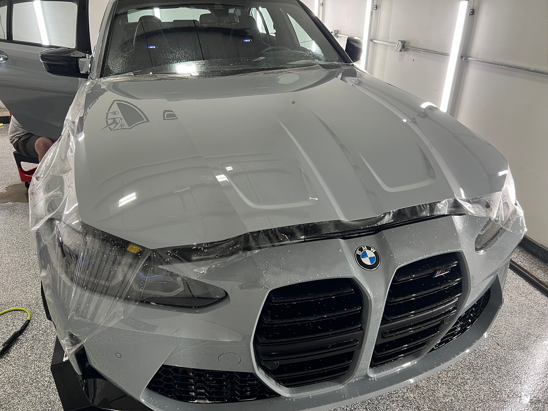 A bmw is covered in ppf wrap in a garage.