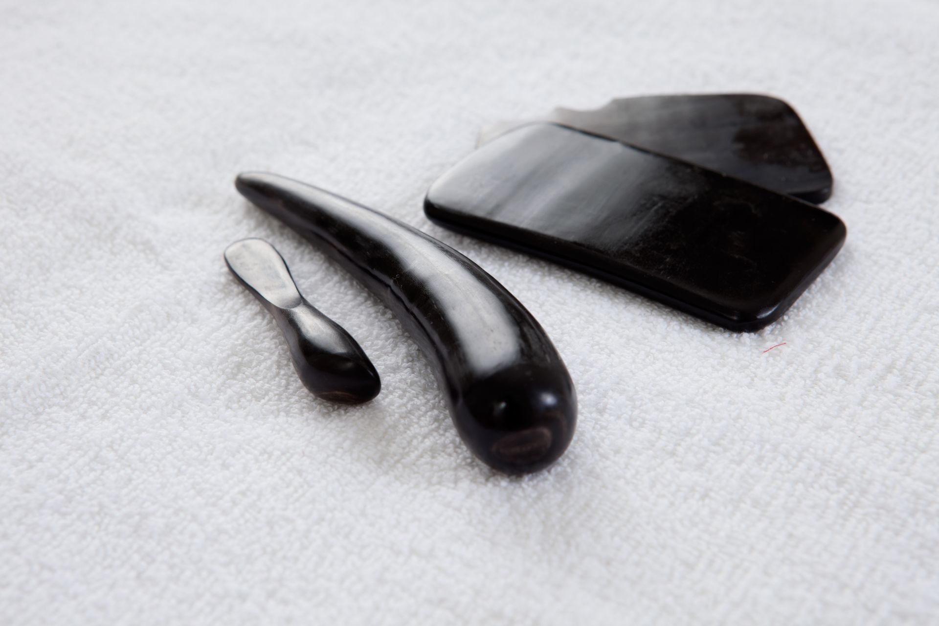 Dark wooden massage tools on a white towel.