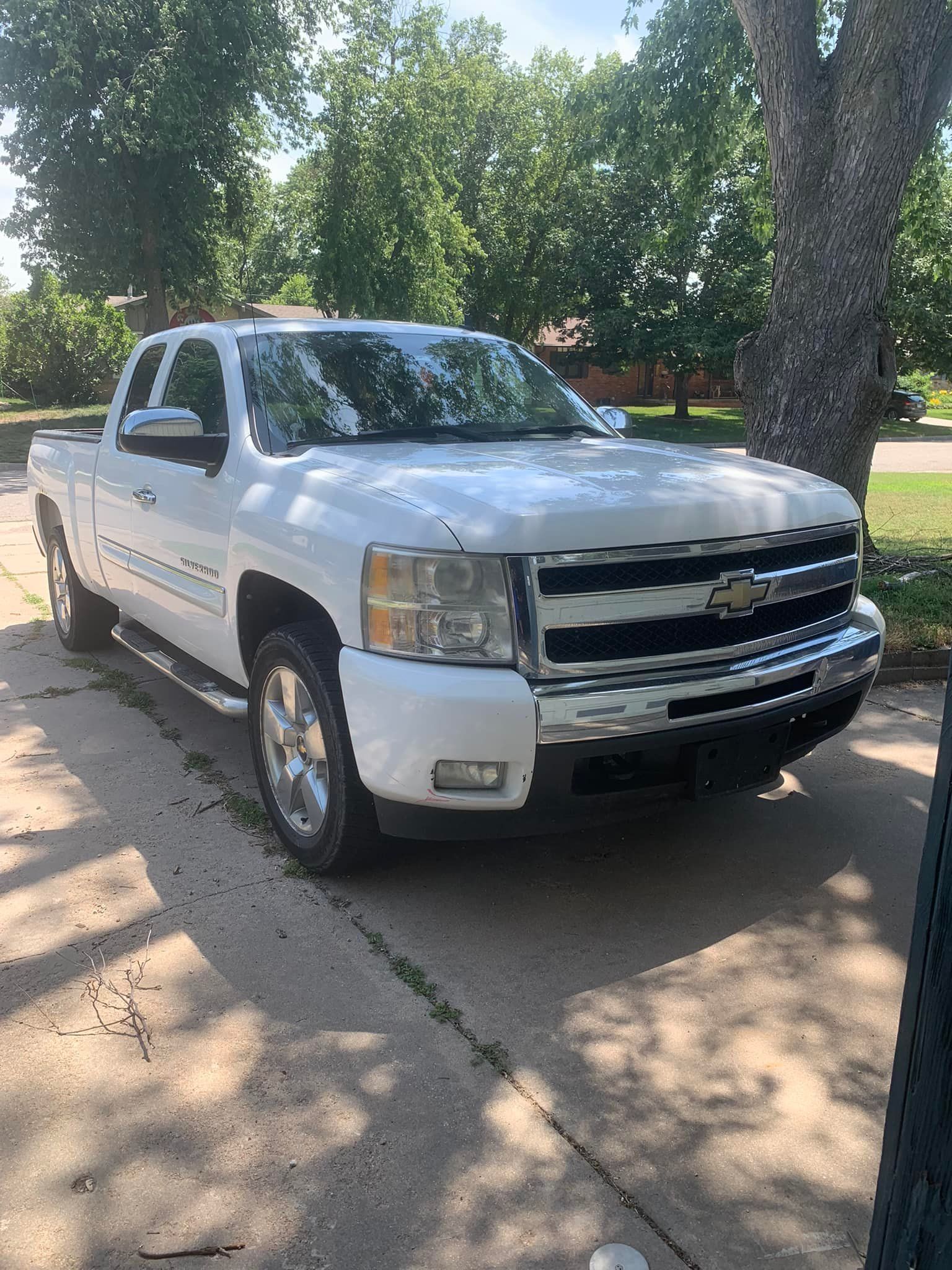 White Chevrolet pickup truck parked on a driveway, sunny day.