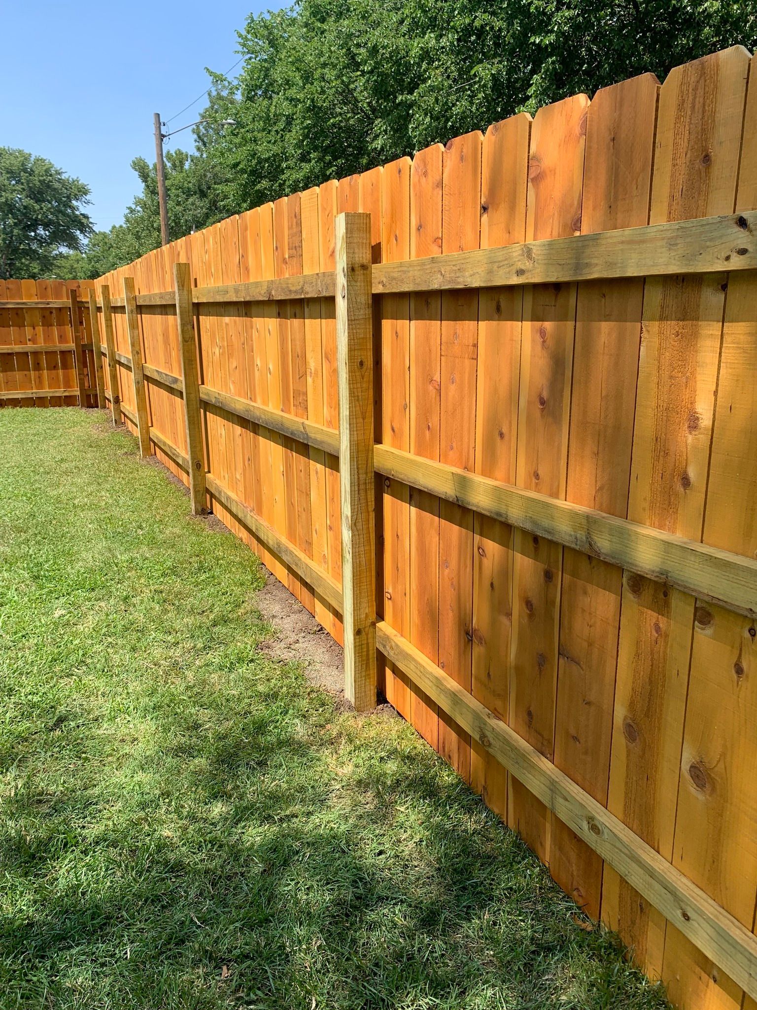 Wooden fence on a green lawn, with a natural stain.