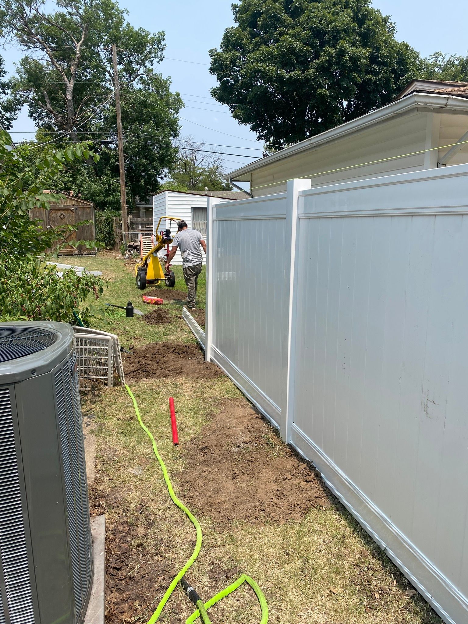 White vinyl fence in a yard, with a post and decorative top.