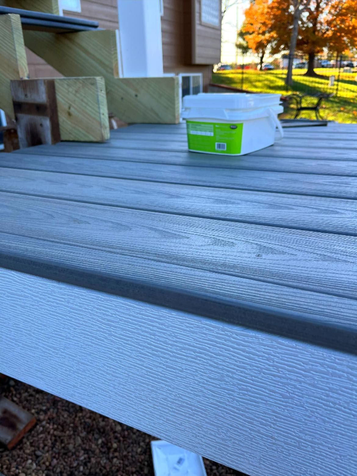 Gray composite deck with white trim, a plastic container, and some wooden blocks.